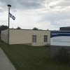 Un bâtiment, un drapeau du Québec et une enseigne en premier plan où il est indiqué, « Hôpital, CLSC et Centre d'hébergement d'Asbestos ». 
