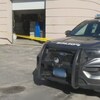 Un voiture de police devant la porte arrière barrée d'un hôtel.