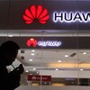 Un homme fume une cigarette devant l'entrée d'un magasin Huawei.