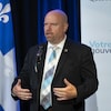 Ian Lafrenière s'adresse à des journalistes devant un drapeau du Québec.