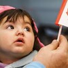 Une jeune réfugiée syrienne regarde un petit drapeau du Canada.