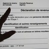 L'ombre d'une main pointe une ligne d'une déclaration de revenus qui apparaît sur un écran d'ordinateur.