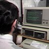 Un homme assis à un poste informatique avec un relevé T4 posé sur le clavier.