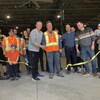 Le maire de Sept-Îles coupe le ruban d'inauguration du nouveau hangar de la Ville en compagnie de l'équipe des travaux publics.