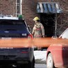 Un pompier sort d'une résidence. Une voiture de police est stationnée à proximité.