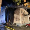 Une maison en feu avec une nacelle de pompier au devant.