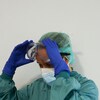 Une travailleuse de la santé, vêtue de l'équipement personnel contre le coronavirus, ajuste ses lunettes de protection.