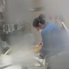 Une infirmière penchée au-dessus d'une personne couchée dans un lit d'hôpital.