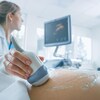 Gros plan sur le ventre d'une femme enceinte, pendant qu'une radiologue réalise une échographie.