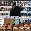 Un homme se tient debout dans un rayon de produits laitiers pour faire son épicerie. 