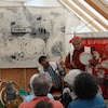 Deux hommes en tenue traditionnelle font une prestation devant un public à Innucadie.