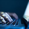 Un homme pose ses mains sur le clavier d'un ordinateur portable dans l'obscurité.