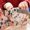 Une femme coupe un morceau de viande avec d'une couteau tranchant.