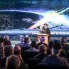 Un homme prononçant un discours devant un auditoire avec en arrière-plan un missile.