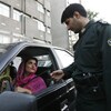 Un policier demande à une femme portant des vêtements de couleur vive ses papiers d'identité à un poste de contrôle de la police des mœurs à Téhéran.
