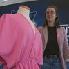 Une femme présente une tunique rose sur un mannequin.