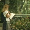 Femme debout qui regarde des plantes en prenant des notes dans un cahier.