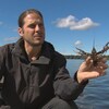 On voit M. Desroches, au bord d'un lac, qui tient une écrevisse dans sa main.