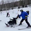 Le moniteur montre à l'enfant comment se servir de de son siège à skis.