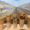 Quelques vases en céramique sur lesquels on peut voir des images d'une famille chinoise. En arrière-plan on peut voir la projection d'une image d'un chemin de fer. 