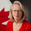 Jennifer May pose pour une photo devant un drapeau du Canada. 