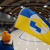Une personne agite un drapeau géant aux couleurs de l'équipe de l'Est-du-Québec dans un aréna.