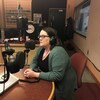 Jillian Kilfoil portant des écouteurs. Elle est assise et parle au microphone dans un studio radio. 