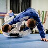 Deux athlètes pratiquant le jiu-jitsu brésilien dans un gymnase.