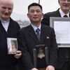 Jo Song-gil, entouré de deux Italiens, tient une cloche ddans ses mains. 