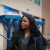 Joelle Kabisoso debout dehors, le regard pensif.