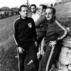 Jo Mallejac, Raymond Charette, Michel Charland et Raymond Beauchemin en survêtement de sport en pause sur une pente gazonnée.