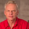 John de Ruiter, vêtu d'une chemise rouge, regarde en face de lui.