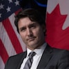 Justin Trudeau est debout devant des drapeaux canadien et américain.