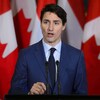 Le premier ministre Justin Trudeau prenant la parole, devant des drapeaux du Canada.