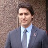 Justin Trudeau debout à l'extérieur, l'air sérieux, devant un édifice en pierres.