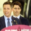 Justin Trudeau, l'air sérieux, en arrière-plan lors d'un point de presse.