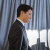 Justin Trudeau vu de côté, marchant devant un rideau.