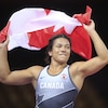 Justina Di Stasio en habit de lutte tient le drapeau du Canada.