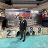 Samir Baccouche, posant dans un amphithéâtre, debout devant l'affiche de la compétition.