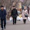 Des piétons transportent des sacs de nourriture dans une rue.