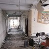 Un couloir d'hôpital a été endommagé lors d'un bombardement. Des chaises sont renversées sur le sol et des câbles pendent du plafond.