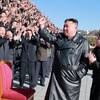 Kim Jong Un, le poing dans les airs, devant une foule d'hommes qui l'applaudient. 