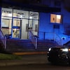 En soirée, une voiture de police devant un bâtiment.