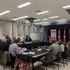 Des représentants de différents organismes fransaskois discutent et sont assis à une table à La Cité.