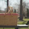 Un panier en osier sur une table de pique-niques dans un parc.