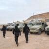 Des soldats près de véhicules militaires dans le désert.