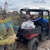 Des gens à bord d'un VTT ramassent des cages à homards, placés à l'arrière du véhicule motorisé. 