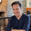 Luc Langevin assit à une table de restaurant devant un mur de brique.