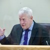 Le coroner en chef adjoint Luc Malouin derrière une baie vitrée.