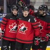 Trois joueurs du Canada en uniforme rouge et noir après avoir célébré un but.